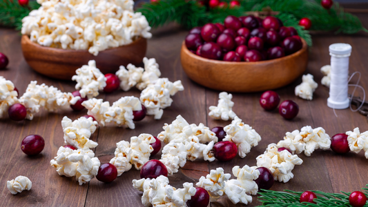 Popcorn and cranberry garland on table with loose supplies.