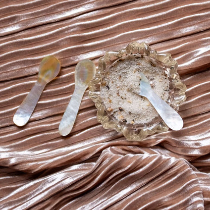 Set of 3 mother of pearl caviar spoons on luxurious velvet. One spoon is dipping into spices.