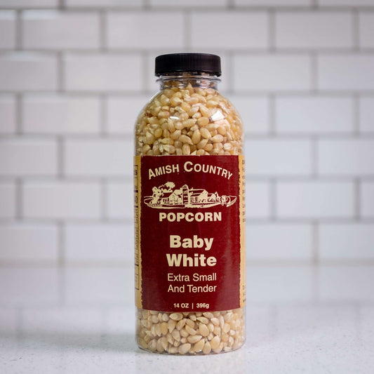 Baby white hulless popcorn kernels by Amish Country Popcorn. Front of 14oz plastic bottle