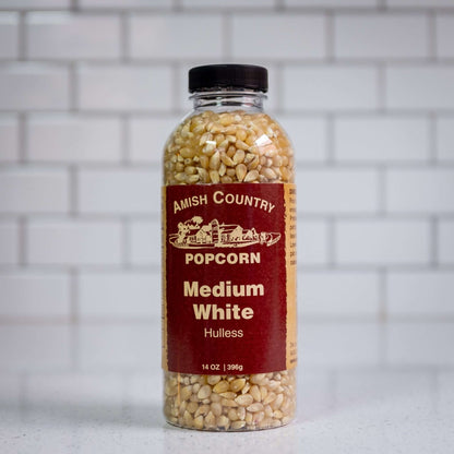 Medium white hulless popcorn kernels by Amish Country Popcorn. Front of 14oz plastic bottle