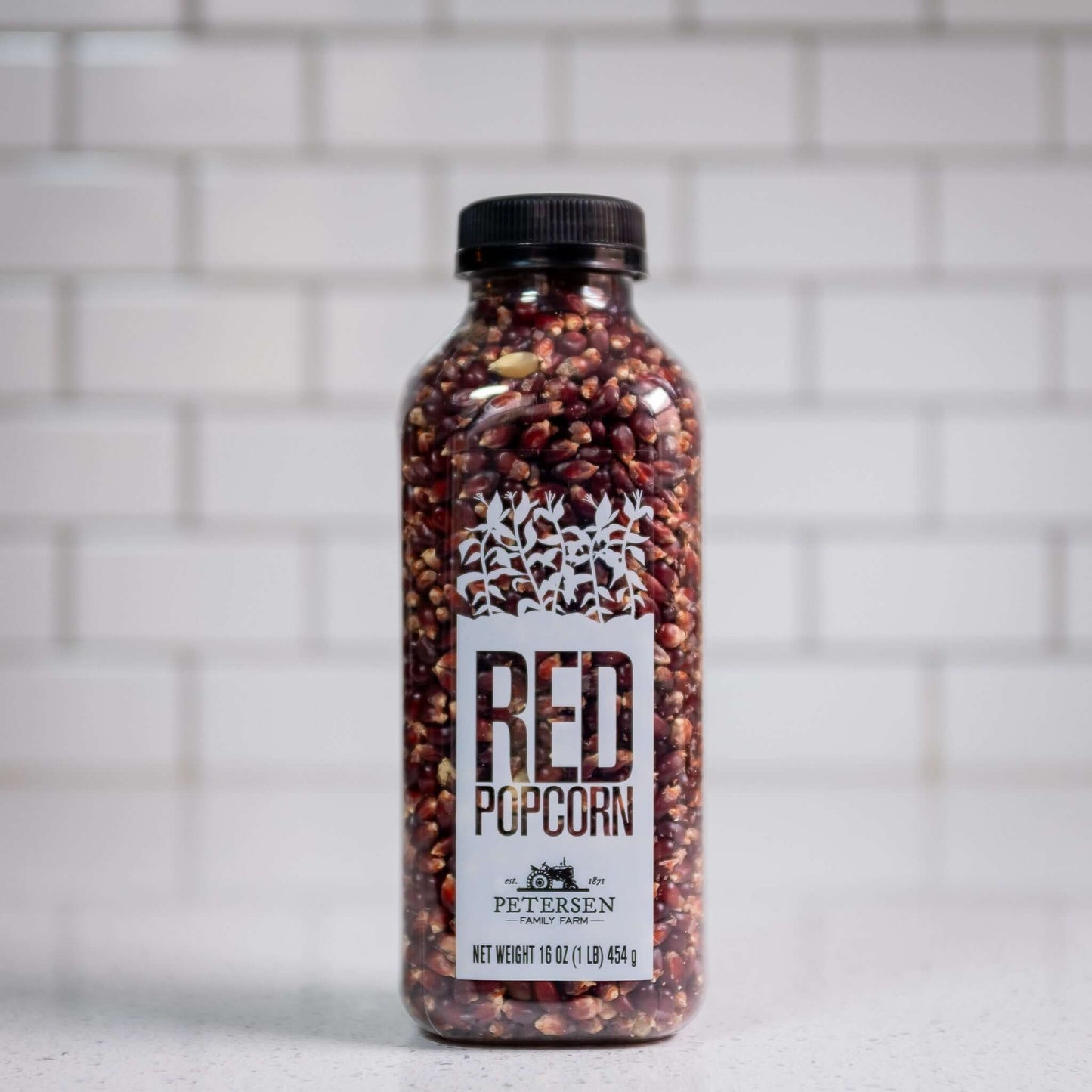 Red popcorn kernels by Petersen Family Farm. 16oz Plastic bottle, front